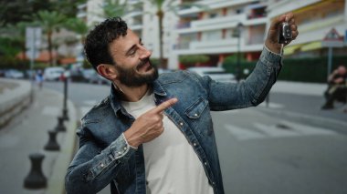 Sakallı İspanyol bir adam canlı bir sokak sahnesinde arabanın anahtarlarını tutuyor, şehir yaşamını ve modern ulaşımı gözler önüne seriyor..