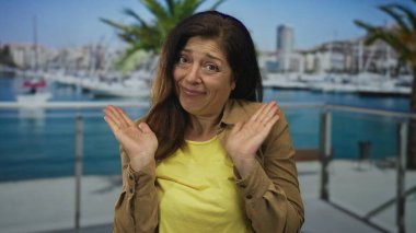 Palmiye ağaçları ve marina manzaralı bir sahil binasında demirlemiş teknelerin yanında el ele tutuşan kadın, minnettarlık..