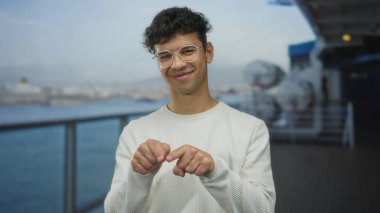 Gözlüklü, beyaz kazaklı, deniz kenarında bulanık yüzen ve arkasında yolcu gemisi olan bir adam. Mutluluk..