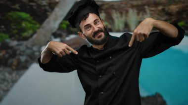 Otelde sakallı İspanyol bir aşçı, bir otelde sırıtıyor, ceketini doğal ve mavi suların arka planına gösteriyordu..