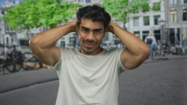 Güneşli şehir sokağında başı arkasında elleri olan adam bisiklet ve ağaçlarla dolu; huzur dolu yalnızlık..