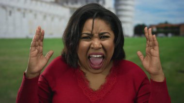 İtalya 'daki ikonik sidik kulesinin yanında öfkesini dışa vuran, kırmızı giyinen, yoğun duygular besleyen, büyük boy İspanyol bir turistin ısıtmalı tepkisini yakalayan bir kadın..