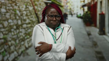 Steteskoplu bir kadın soğuk algınlığından titreyen, gözlüklü ve beyaz ceketli, şehir manzarası ile çevrili, soğuk bir hava veriyor..