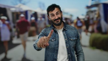 Sokak ortasında sakallı İspanyol bir adam. Çevresi insanlarla çevrili, hareketli şehir ortamında parmağıyla hareket etmiyor..