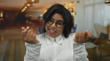 Kapalı bir otelde gülümseyen gözlüklü bir kadın rahat ortam ortamında para harcıyor ve finansal mizah gösteriyor..