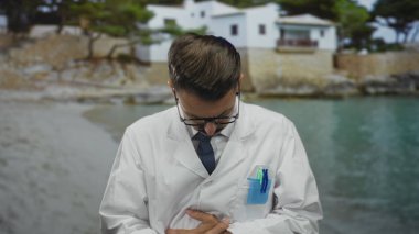 Beyaz önlüklü ve mavi kravatlı bilim adamı kalp krizi için deniz kenarında elini göğsüne koydu..