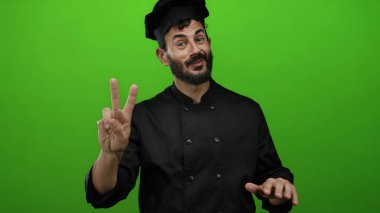 Parlak yeşil bir altyapısı olan, siyah üniformalı ve şapka takan, sakallı İspanyol aşçı şefi..