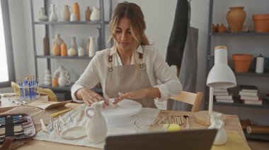 Kadın, sanatsal stüdyoda çıplak elle kil şekillendiriyor; yaratıcılık odaklı sakinlik.