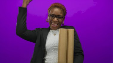 Mimar kadın elinde iki rulo planla mor stüdyoda dururken yumruk tokuşturuyor. Gurur..