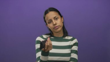 Gözleri kapalı televizyon kumandası tutan bir kadın mor bir arka planda duruyor. Rahatlamayı ve odaklanmayı öneriyor. Yeşil ve beyaz bir kazak giyiyor..