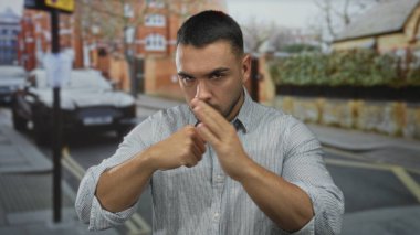 İspanyol genç adam kalabalık şehir caddesinde çıplak avucuna yumruk attı; öfke çatışması kararlılığı.