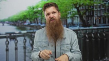 Sakallı bir adam, Kanal Caddesi Köprüsü 'nde gözlerinin yanında yumruklarını sıkarak sahte ağlama hareketi yapıyor..