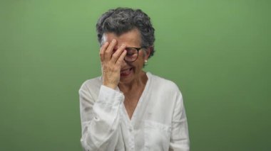 Gri saçlı yaşlı bir kadın canlı yeşil bir arka plana karşı el ele gülüyor, neşe ve pozitifliği ifade ediyor..