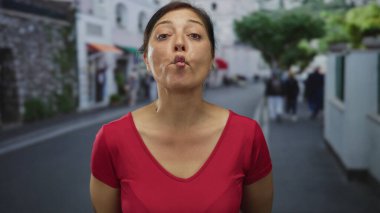 Kadın dudaklarını büzüyor ve başını hafifçe eğiyor. Sıcak güneş ışığı altında şehir caddesinde dururken ıslık çalıyormuş gibi..