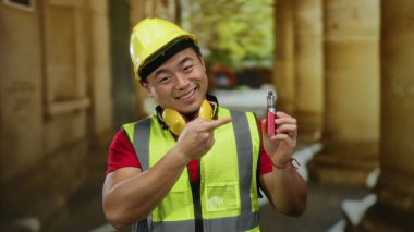 Güvenlik teçhizatlı genç adam eski üniversite binasının içinde kendine güvenle gülümsüyor..