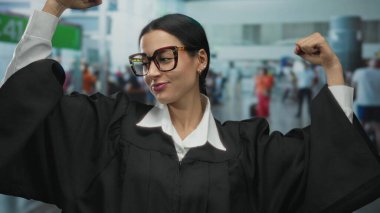 Siyah cüppeli bir kadın yargıcın, kapalı alandaki hareketli kollarını esnetmesi, güçlendirme ve profesyonel bir ortamda kendine güveni canlandırması..