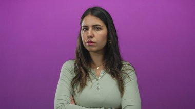 Uzun saçlı genç bir kadın mor bir arka plana karşı duruyor. İzole edilmiş bir stüdyo ortamında ciddi bir düşünce ve tefekkür yapıyor..