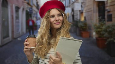 Kadın sokakta çizim defterini tutmadan önce kahvesini yudumluyor. Seyircilerin önünde eskiz defterini gösteriyor. Gözlüklü genç sarışın bir öğrenci, açık hava atölyesinde dalgın dalgın görünüyor..