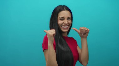 Kırmızı tişörtlü İspanyol kadın geriye doğru neşeli bir gülümsemeyle parlak mavi duvarlı izole edilmiş arka planda..