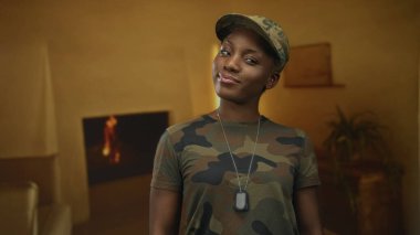 Kadın, elinde künyeyle, kamuflaj üniformasıyla ayakta duruyor..