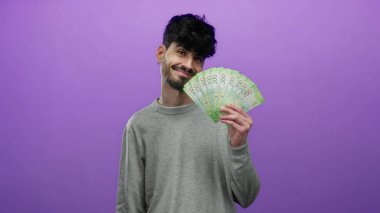 Canlı mor bir arka planda Rus rublesi tutan adam, kendine güvenen bir gülümsemeyle zenginlik ve ekonomik konsept sergiliyor..