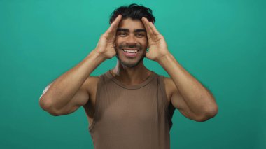 Stüdyoda elleri parlak yeşil arkaplan ile yüzünü kaplayan adam neşeli ifadeler yaparken; neşe.