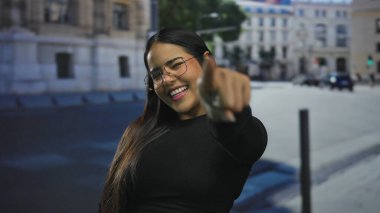 Kalabalık bir caddede şehir ortamında neşeli bir ifadeyle gezen bir kadın..