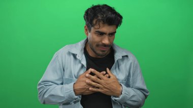 Genç İspanyol adam, yeşil stüdyoda avuçlarıyla ve çatık kaşlarıyla duraksamayı başarıyor..