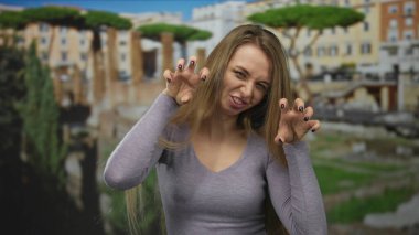 Antik Roma harabelerinde şakacı genç bir kadın canlı bir ifadeyle arka planda, açık havada sembolik Roma ortamında eğlenceli anlar sergiliyor..