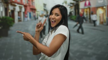 Gülümseyen uzun saçlı genç Latin kadın sokaklarda heyecan verici bir şekilde dolaşıyor. Etrafı şehirli dükkanlar ve renkli binalarla çevrili. Hispanik canlılık ve açık hava etkileşimleriyle dolu..