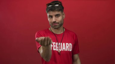 Cankurtaran, parlak kırmızı stüdyo ortamında boynunda asılı gümüş düdük ile elini teklif; güven.