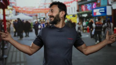 İspanyol asıllı sakallı bir adam renkli bayraklarla dolu kalabalık bir caddede şakacı hareketler yapıyor. Gün içinde açık hava sahnesinde bulanık kalabalıkla çevrili..