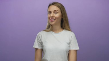 İzole edilmiş mor arka planda gülümseyen bir kadın beyaz gömlek giyiyor. Genç ve neşeli bir bayan, mutluluğu ve basitliği simgeliyor..