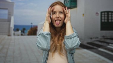 Kadın yüzünü ellerle kapatıyor ve sokaktaki beyaz binanın önündeki parmakların arasından gözetliyor; oyuncu merak..