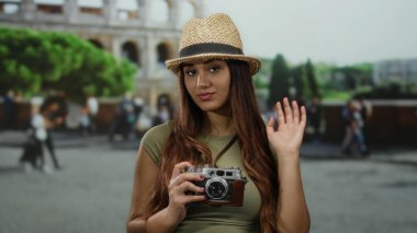 Roma Kolezyumu 'na el sallayan genç İspanyol kadın Roma, İtalya' da seyahat ve keşif sergiliyor. Turist olarak rolünü vurguluyor. Açık havada anılarını yakalıyor..
