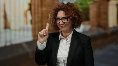 Şehir caddesinde kendine güvenen gözlüklü bir kadın. Bulanık şehir geçmişi var. Farklı orta yaş tarzını açık havada gösteriyor..