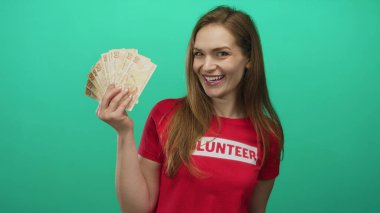 Yeşil stüdyoda elinde lira banknotları tutan gülümseyen beyaz bir kadın..