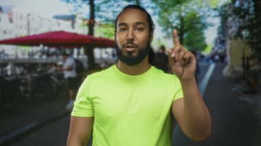 İşlek bir caddedeki açık hava restoranının terasında konuşurken adam parmağını yukarı kaldırır; güven talimatı.