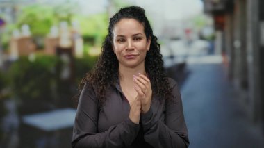 Terasta neşeli bir şekilde gülümseyen kadın, arka planda canlı bir sokak bulunan canlı, kentsel bir sahneyi yakalar, mutluluk ve rahatlamış bir ortam hissi taşır..