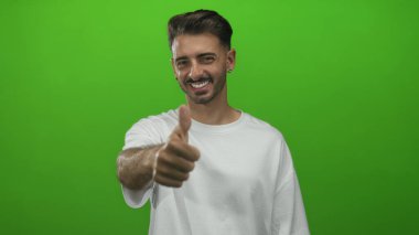 Erkek, canlı yeşil bir stüdyo duvarına karşı başparmağıyla kolunu kaldırır. Pozitiflik..