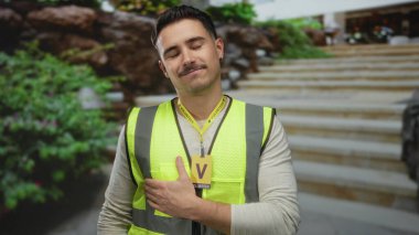 Yansıtıcı yelek giyen genç bir adam şehir sokaklarında tatmin edici bir şekilde gülümsüyor, kendini işine adamış bir gönüllünün ruhunu somutlaştırıyor..