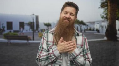 Ekose gömlek giyen adam gün ışığında yıkanan beyaz bir binanın yanında el ele tutuşuyor..