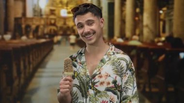 Çiçekli gömlek ve güneş gözlüğü takıp kilisenin içinde dondurma yiyen İspanyol genç adam rahat bir turist havası yayıyor..