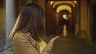 Dışarıda dikilen kadın tarihi üniversite binası koridorunu işaret ediyor; merak keşfi.