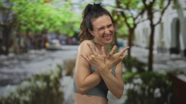 Kadın yüzünü buruşturur ve sokakta ağaçlarla kaplı taş boynuzlarını gösterir; heyecan kutlaması.