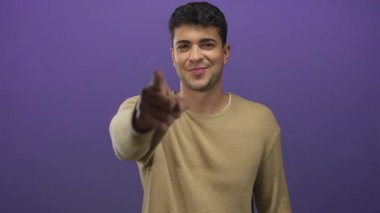 Adam, Latin kökenli genç mankenin sıradan bir erkek tabelasını taklit etmek için mor arkaplan önünde durduğu stüdyoyu ararken elini kaldırır..