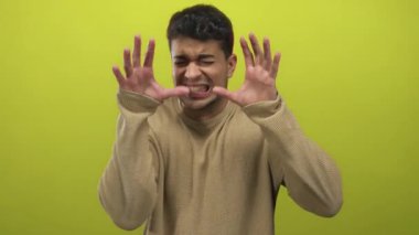 Adam renkli bir arka plana karşı titrek bir jest ile yüzünü bastırır ve genç İspanyol erkek özelliklerini elinde ürkek bir refleks ve yoğun bir ifadeyle gösterir..