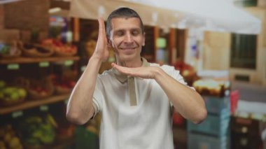 Canlı bir açık hava pazarında arka planda meyve stantları olan bir adam neşeli ve canlı bir atmosfer sergiliyor..