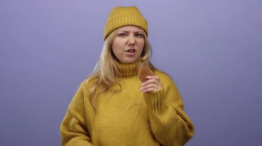 Sarı kazaklı kadın kurabiye jestleri ile hayır mor duvara karşı