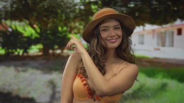 Bikinili kadın parmak gösterirken çıplak omuz gösteriyor; oyuncu özgüven sevinci.